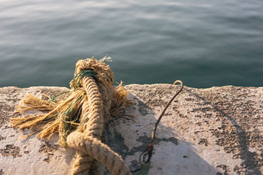 Close-up of a weathered rope on a harbor edge in Mersin, Türkiye, by the sea.