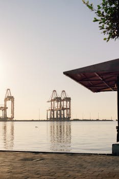 Serene sunset by the waterfront in Mersin, Türkiye, showcasing industrial port cranes.
