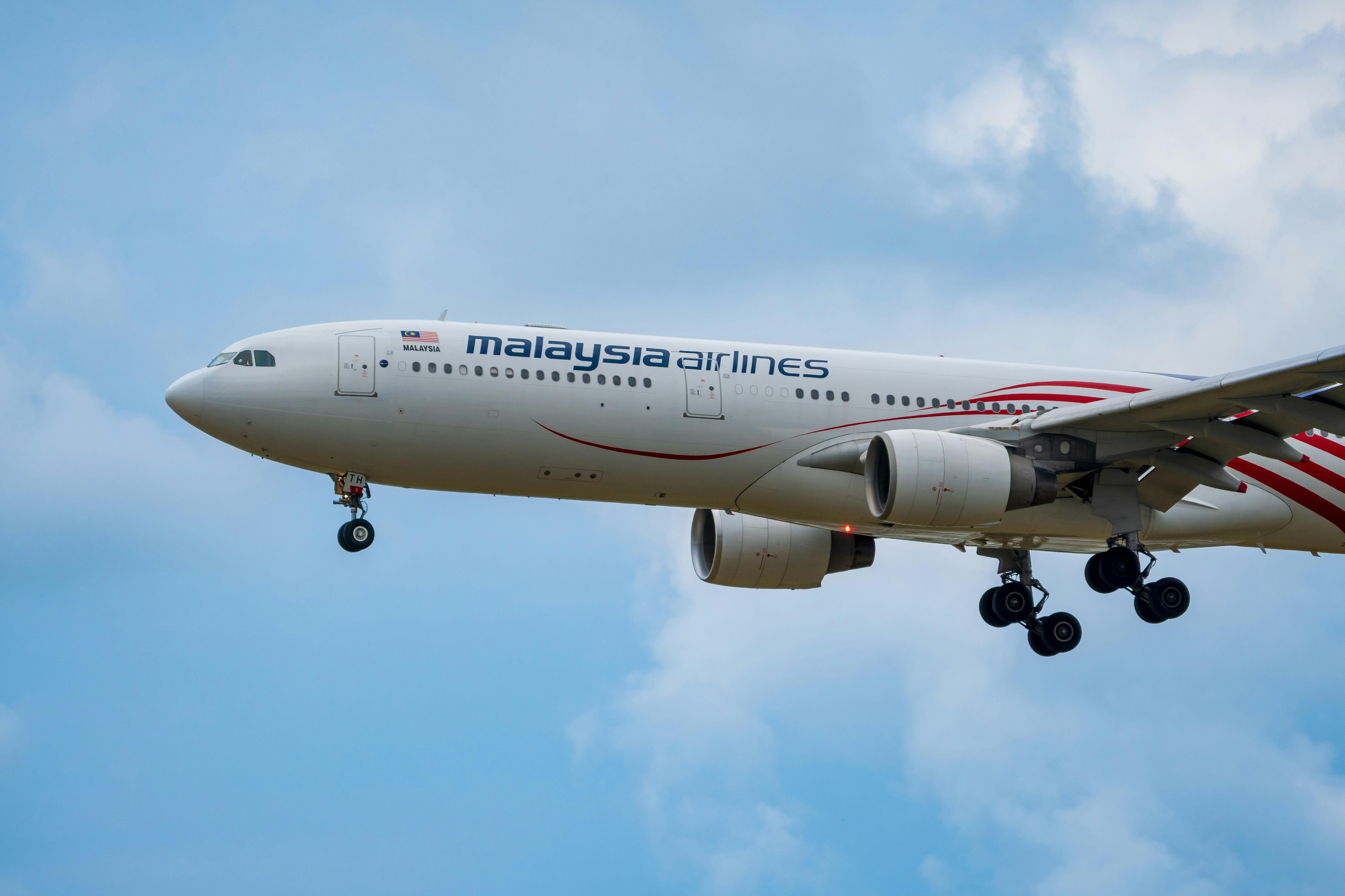 Free Malaysia Airlines plane in the sky moments before landing against a blue sky backdrop. Stock Photo