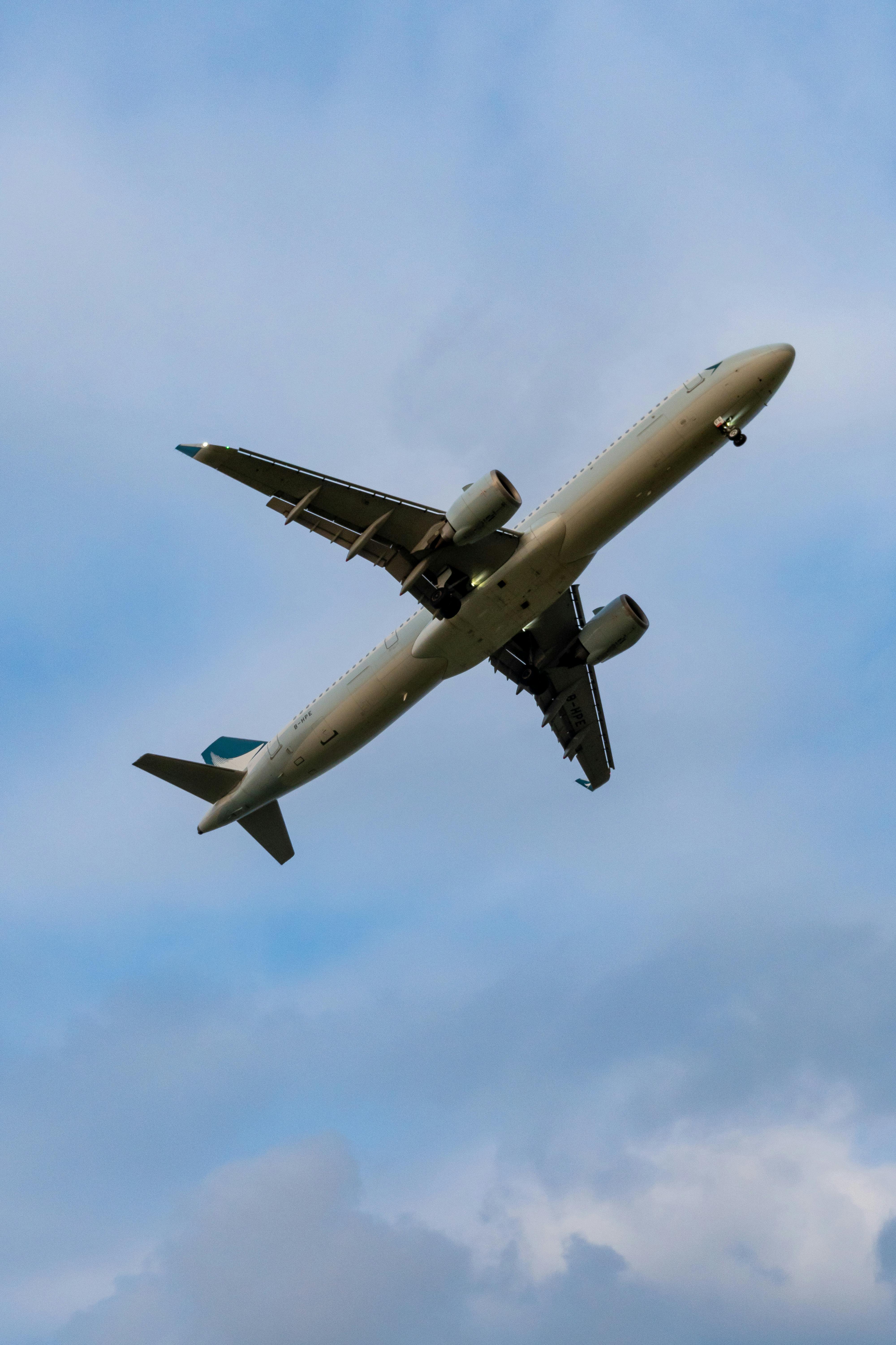 Free A commercial airplane soaring through a clear blue sky, viewed from below, showcasing its wings and engines. Stock Photo