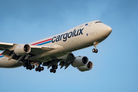 A Cargolux cargo plane flies against a clear blue sky, showcasing its massive structure.