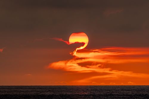 Free Stunning sunset with vibrant orange sky and clouds over the ocean, creating a dramatic seascape. Stock Photo