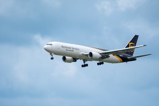 A commercial airplane branded as Worldwide Services flying against a backdrop of a blue sky with clouds.
