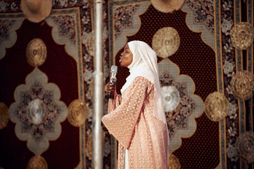 A woman in traditional attire sings into a microphone against an ornate patterned backdrop.