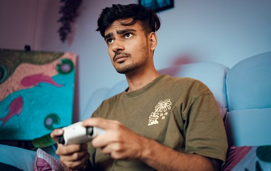 A young man intensely focused on playing video games at home with a controller.