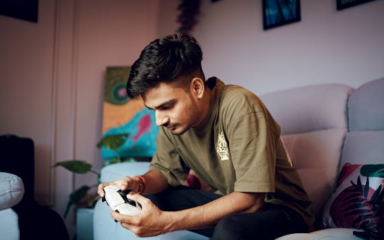 A young man intensely focused on gaming at home with a PS5 controller.