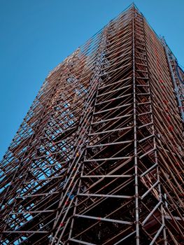 Tall scaffolding structure reaching into clear blue sky.