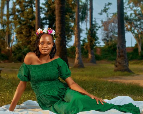 Free A woman in a green dress with floral crown, captured in a tranquil outdoor setting. Stock Photo