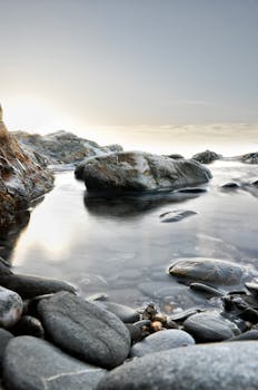 日出时分，英国冈瓦尔明斯特水边岩石与鹅卵石的宁静景色