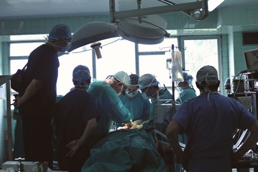Medical team conducting surgery in a hospital setting with focused attention.