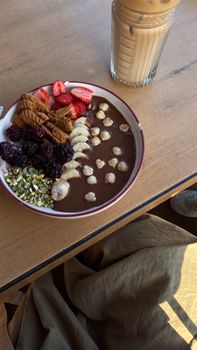 Yummy chocolate smoothie bowl with fresh berries, bananas, cookies, and nuts.