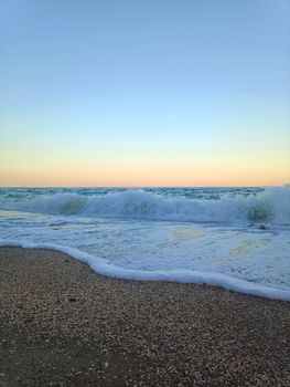 Calm ocean waves gently crashing on a sandy beach at sunset, creating a serene atmosphere.