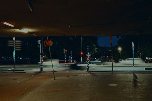 Urban street scene at night with motion blur light trails, underpass view.