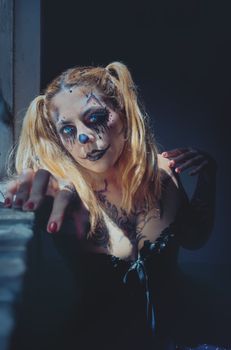 A woman with dramatic clown makeup poses in moody lighting, creating an eerie and artistic atmosphere.
