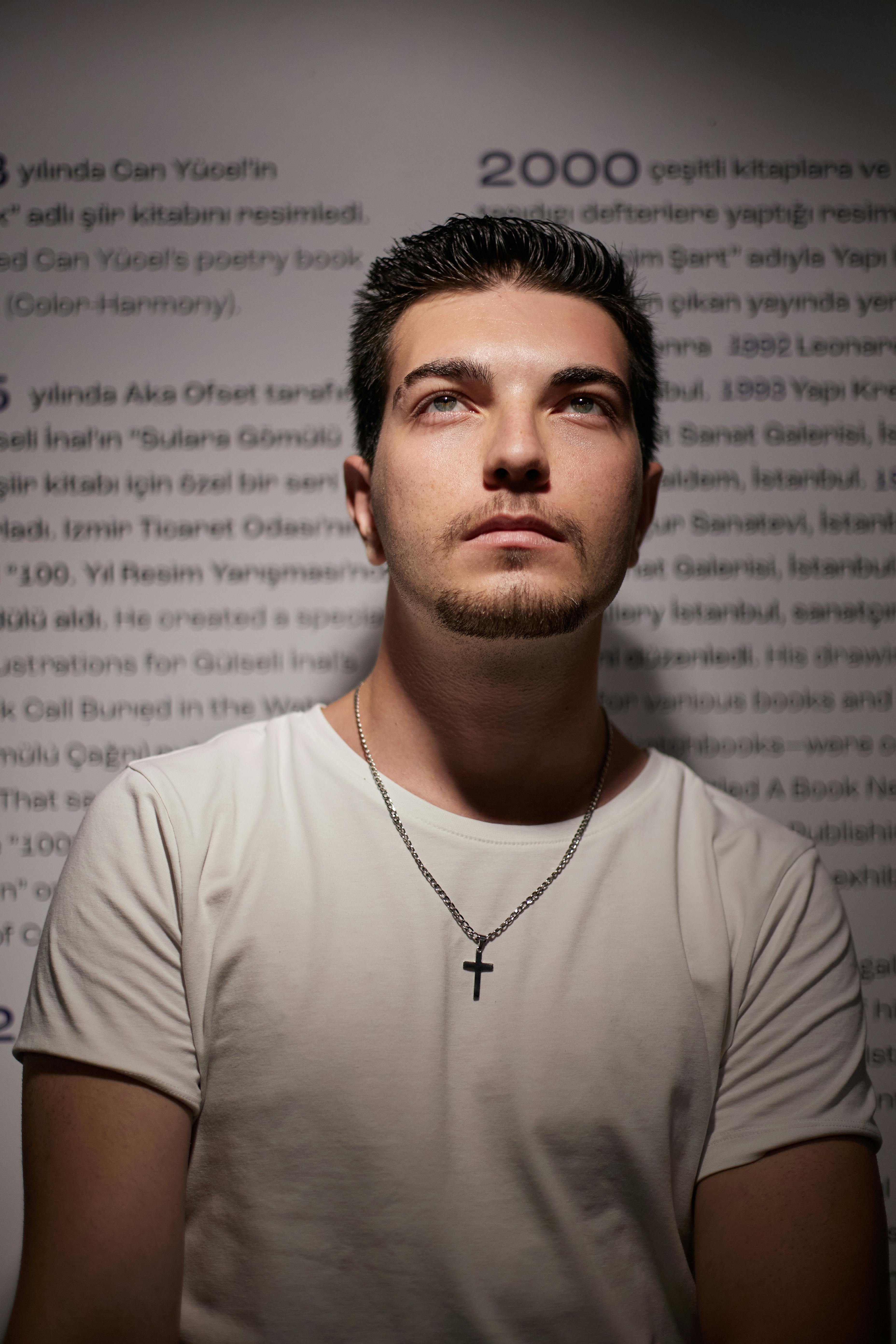 Thoughtful man with a cross necklace in soft indoor light.