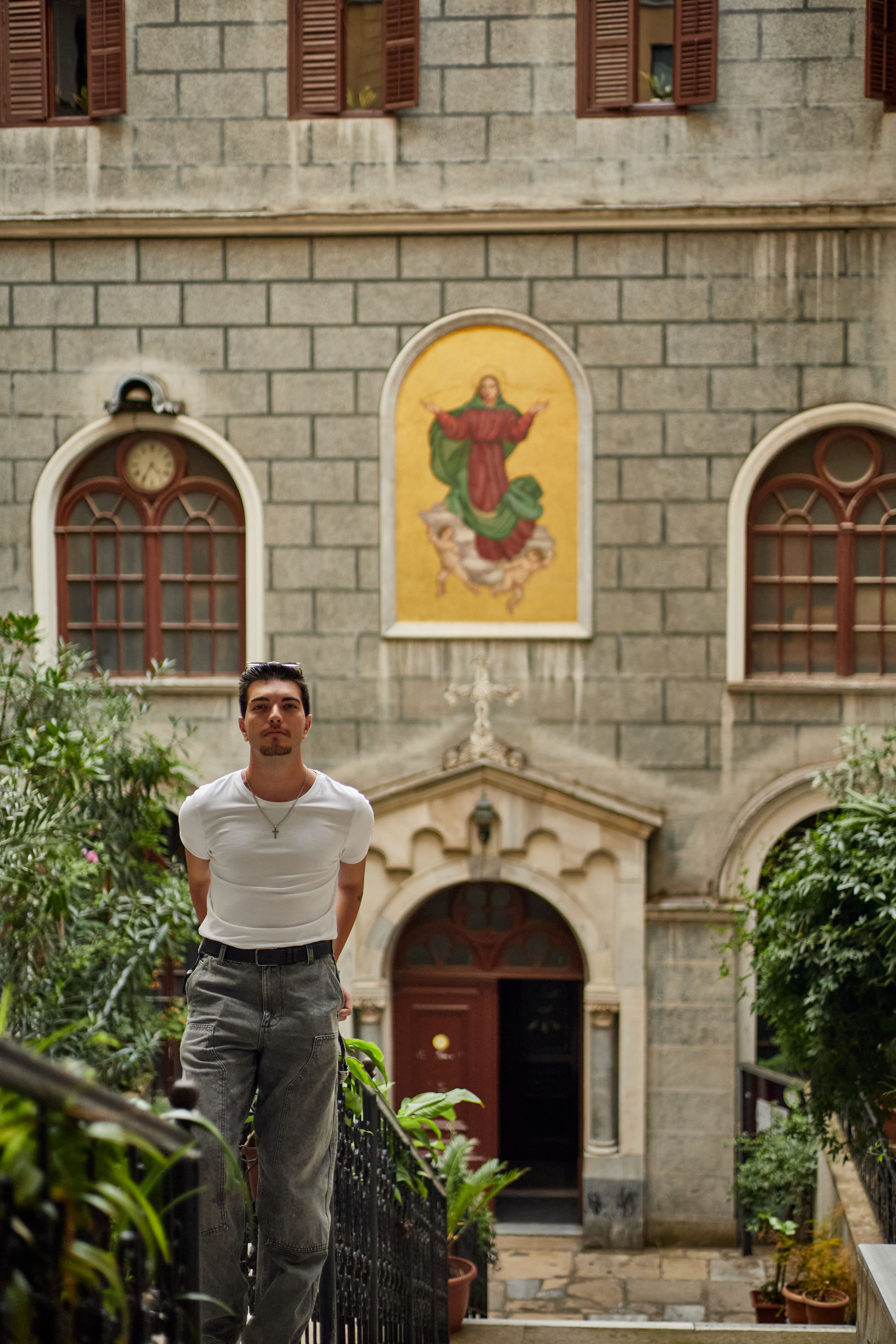 Man standing in front of a historic building in İstanbul with religious artwork.