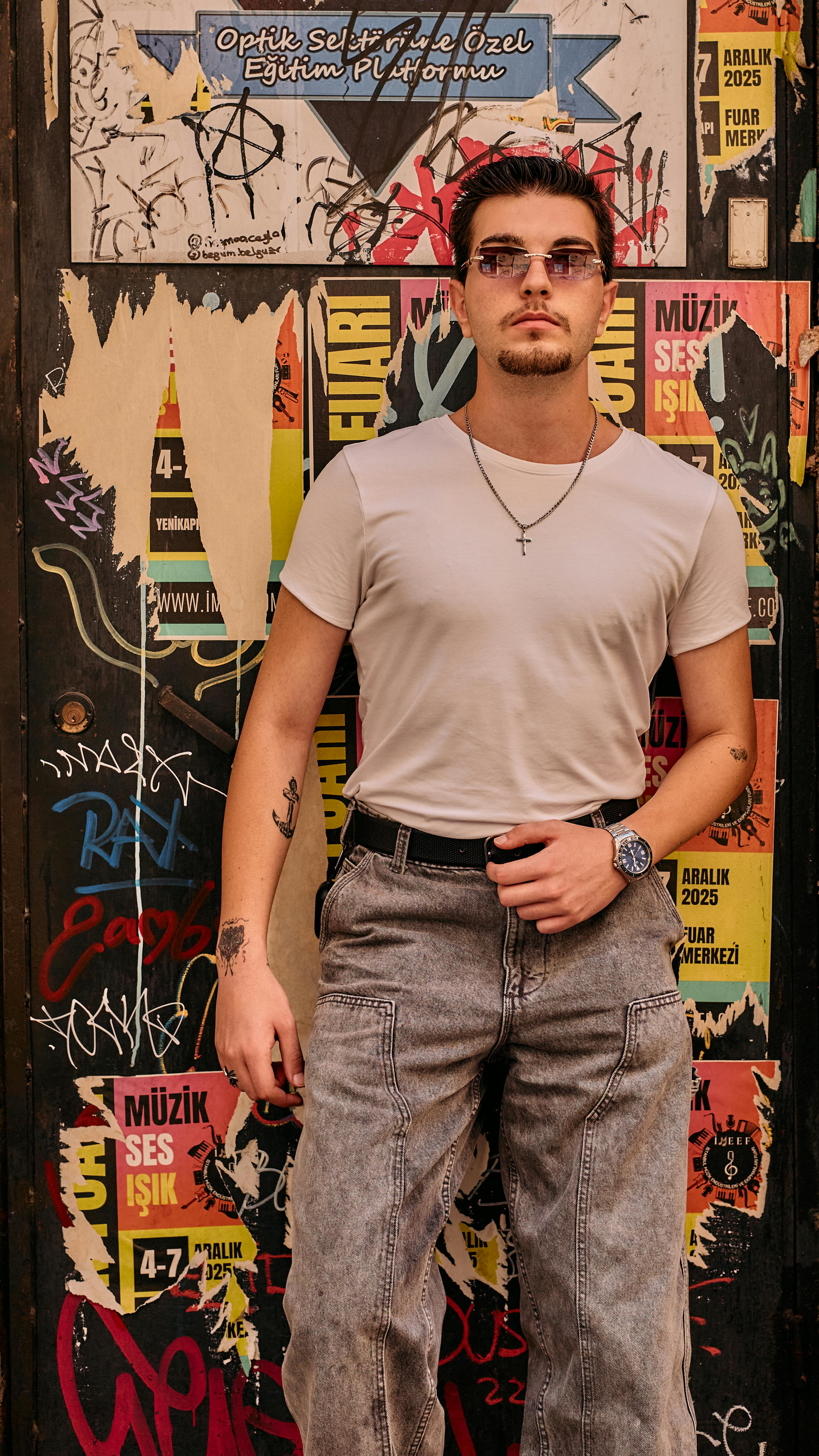 Portrait of a stylish young man standing against a graffiti wall in İstanbul, showcasing urban fashion.