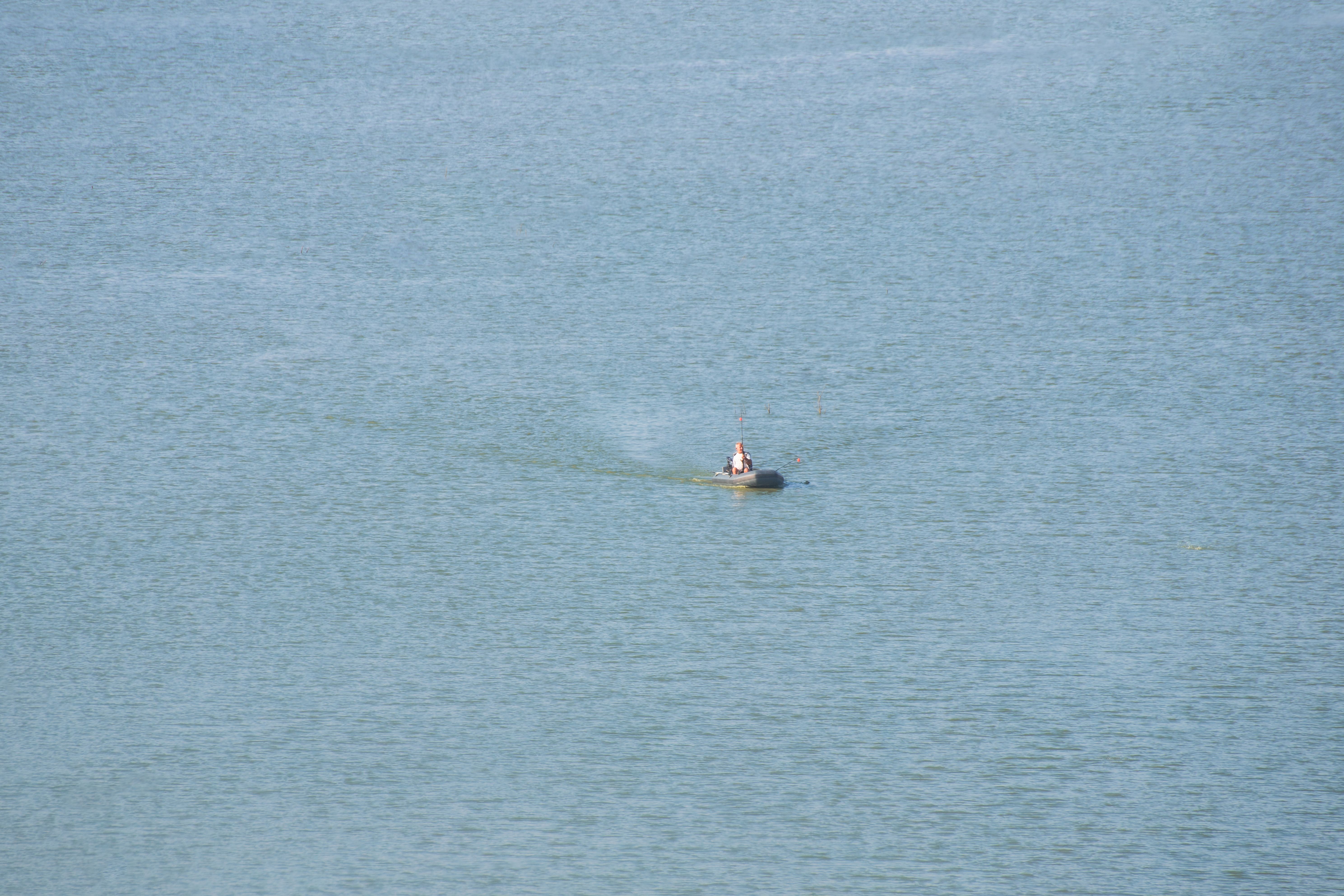Aerial view of a solitary boat navigating calm waters under a clear sky. Aerial view of a solitary boat navigating calm waters under a clear sky.
