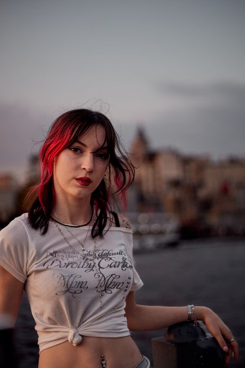 Free Stylish woman with red highlights poses against the Galata backdrop at sunset, capturing Istanbul's vibrant vibe. Stock Photo