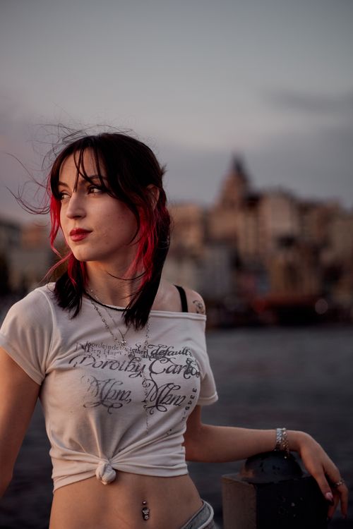 Free Chic young woman posing against a stunning sunset backdrop of Galata Tower, Istanbul. Stock Photo