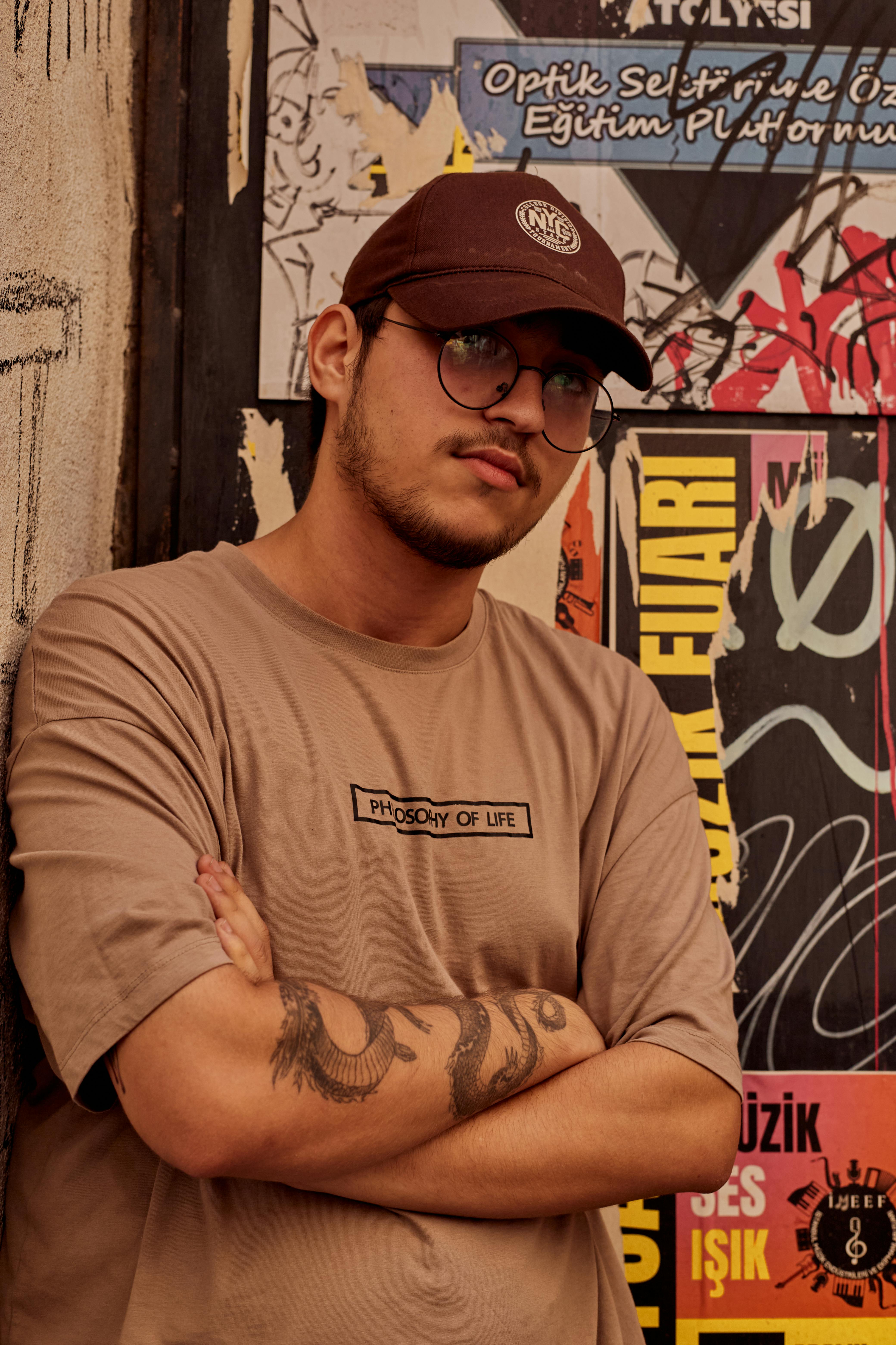 Fashionable young man with tattoos poses against vibrant street art in Istanbul.