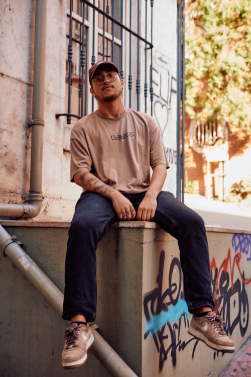 Free Stylish young man sitting on a graffiti-covered ledge in İstanbul, exuding a cool and relaxed vibe. Stock Photo
