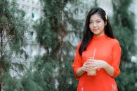 Young Woman in Red Dress Enjoys Refreshing Drink Outdoors