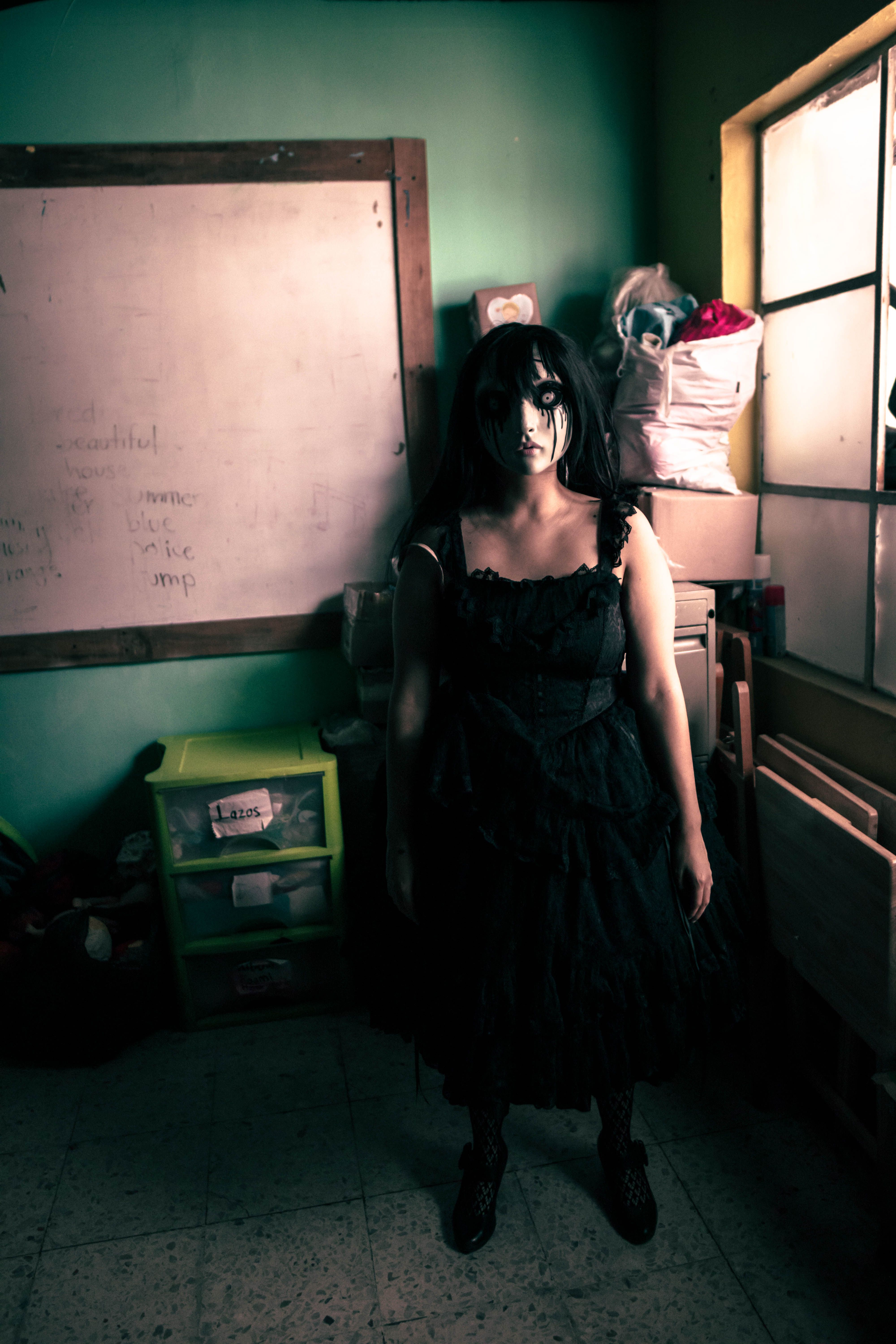Dark, eerie atmosphere with a person in a doll costume standing in a dimly lit room.