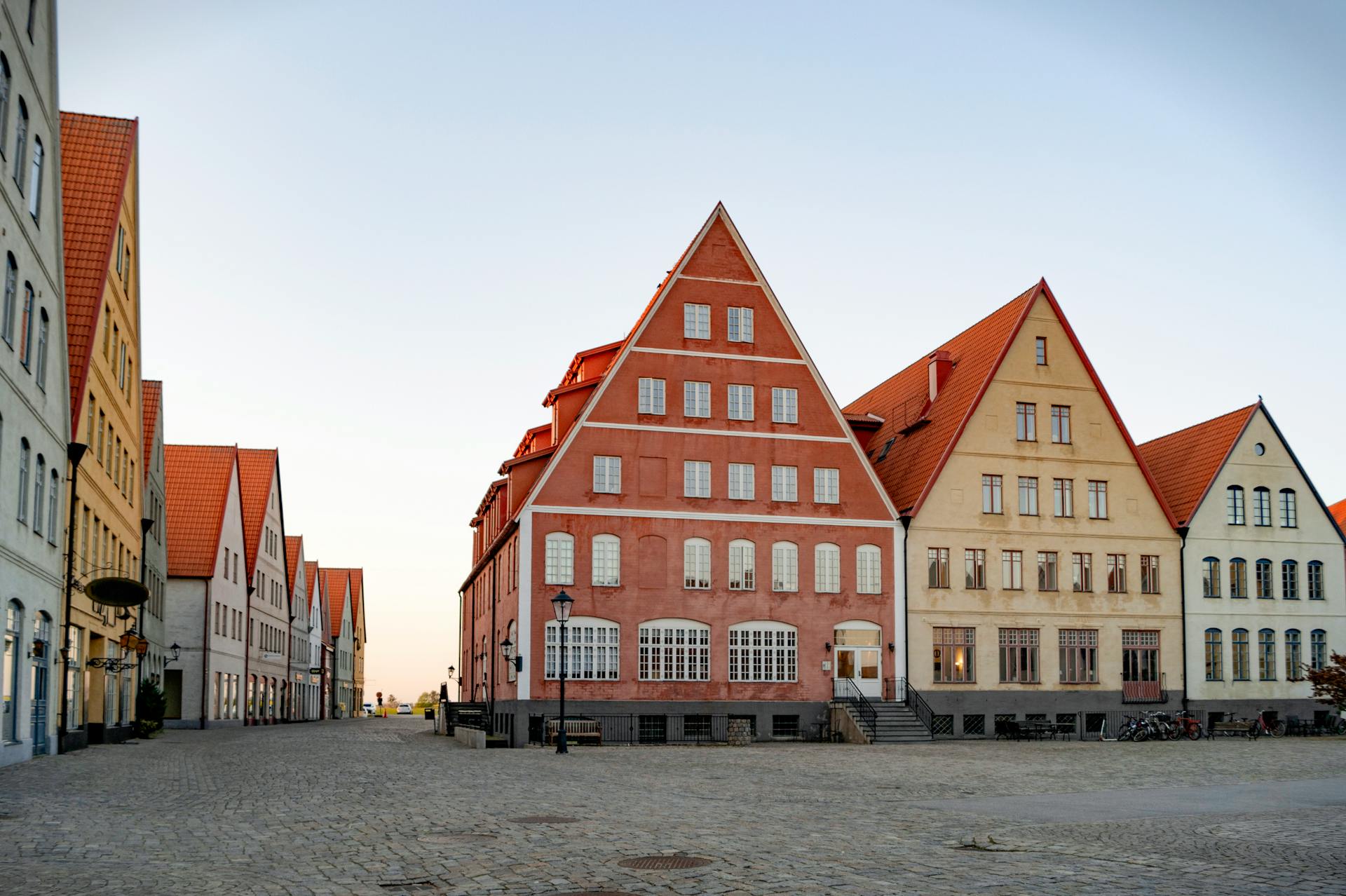 Charming European street with historic buildings featuring red tiled roofs and unique gables.
