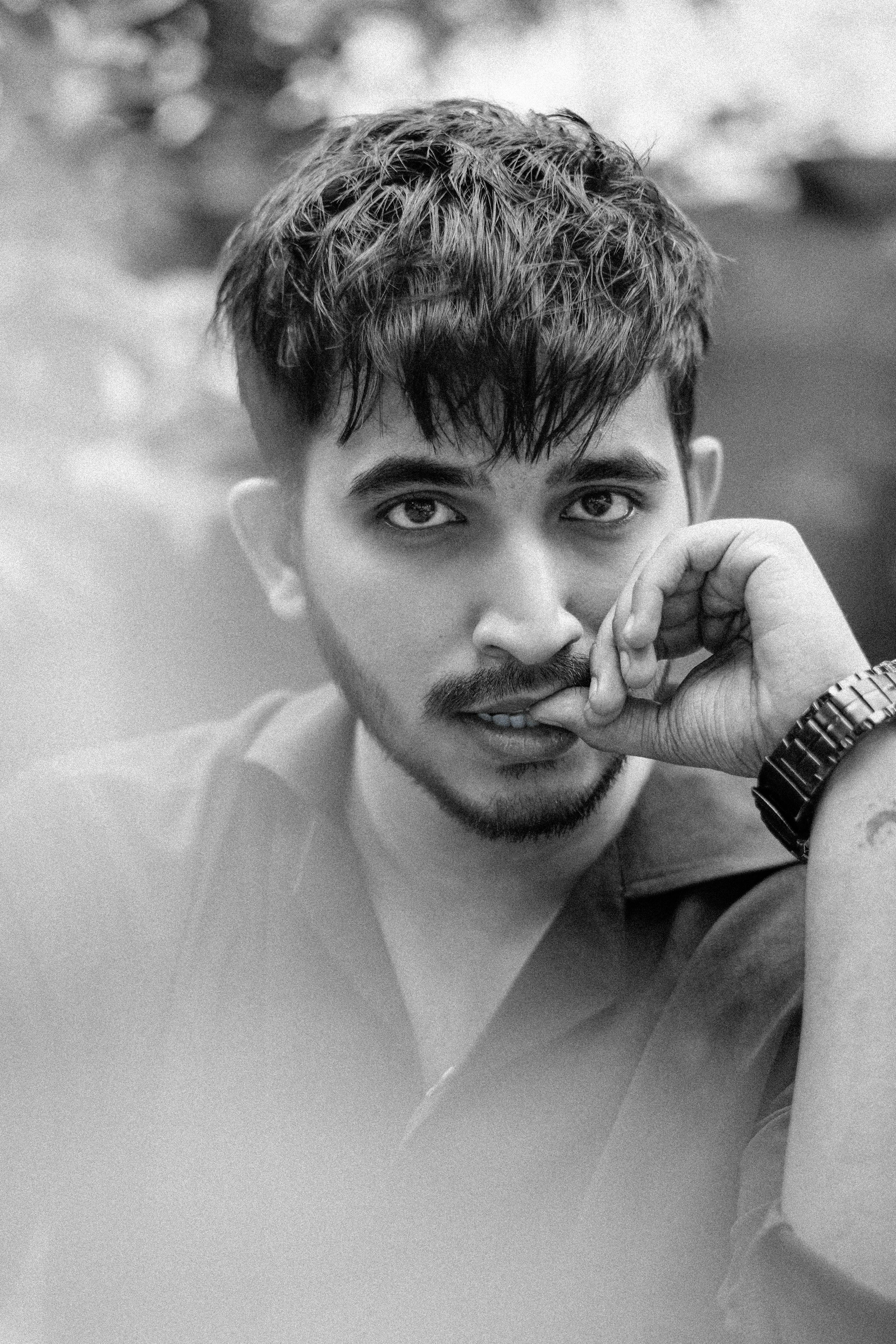Artistic black and white portrait of a pensive young man outdoors.