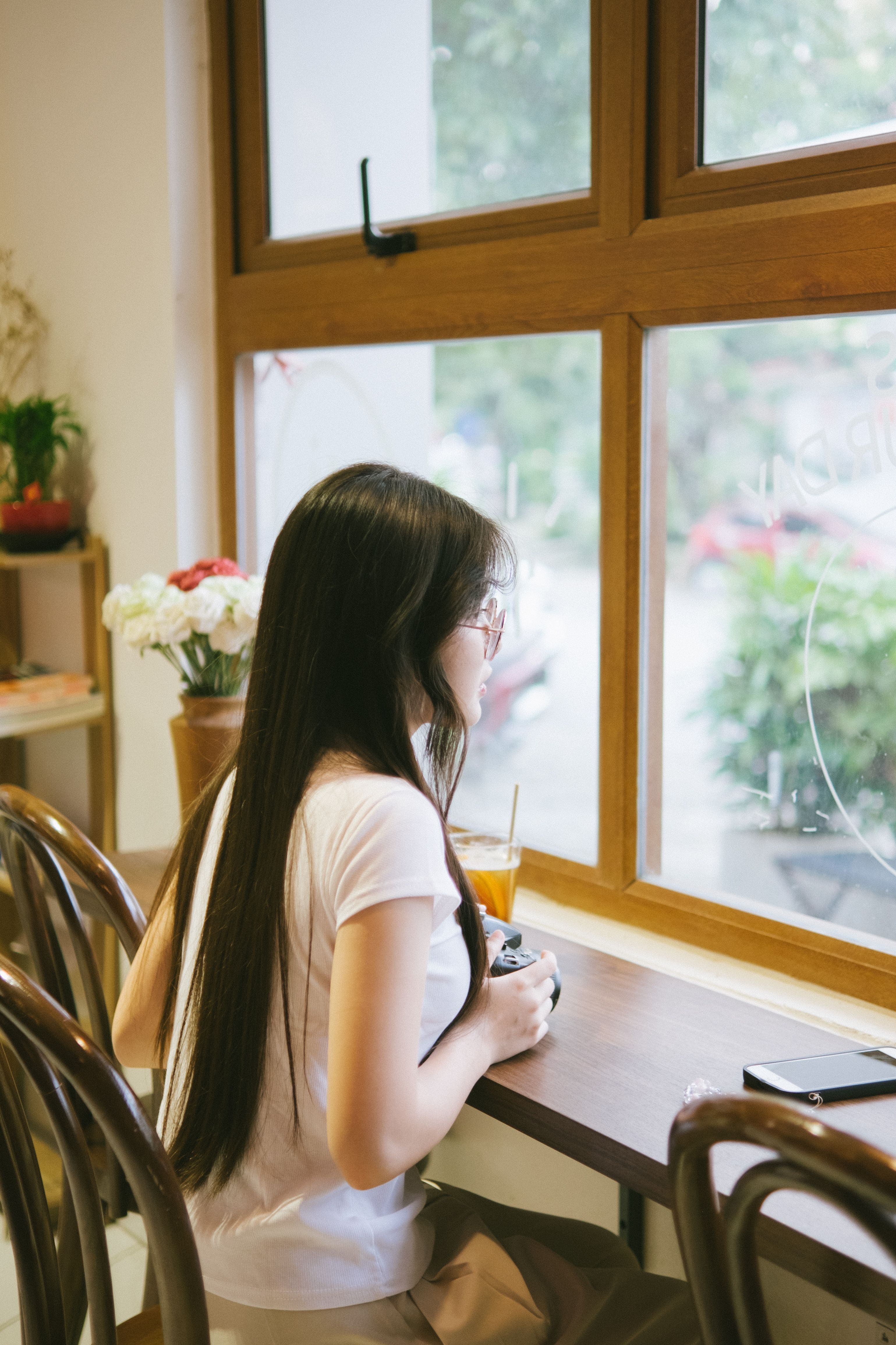 A young woman gazes outside a café window in Lạng Sơn, Vietnam, capturing a serene moment.