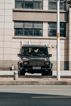 A black luxury SUV parked on an urban street against a modern building facade.