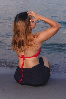 Woman enjoying a serene evening by Lake Ontario, Toronto, in a vibrant red bikini.