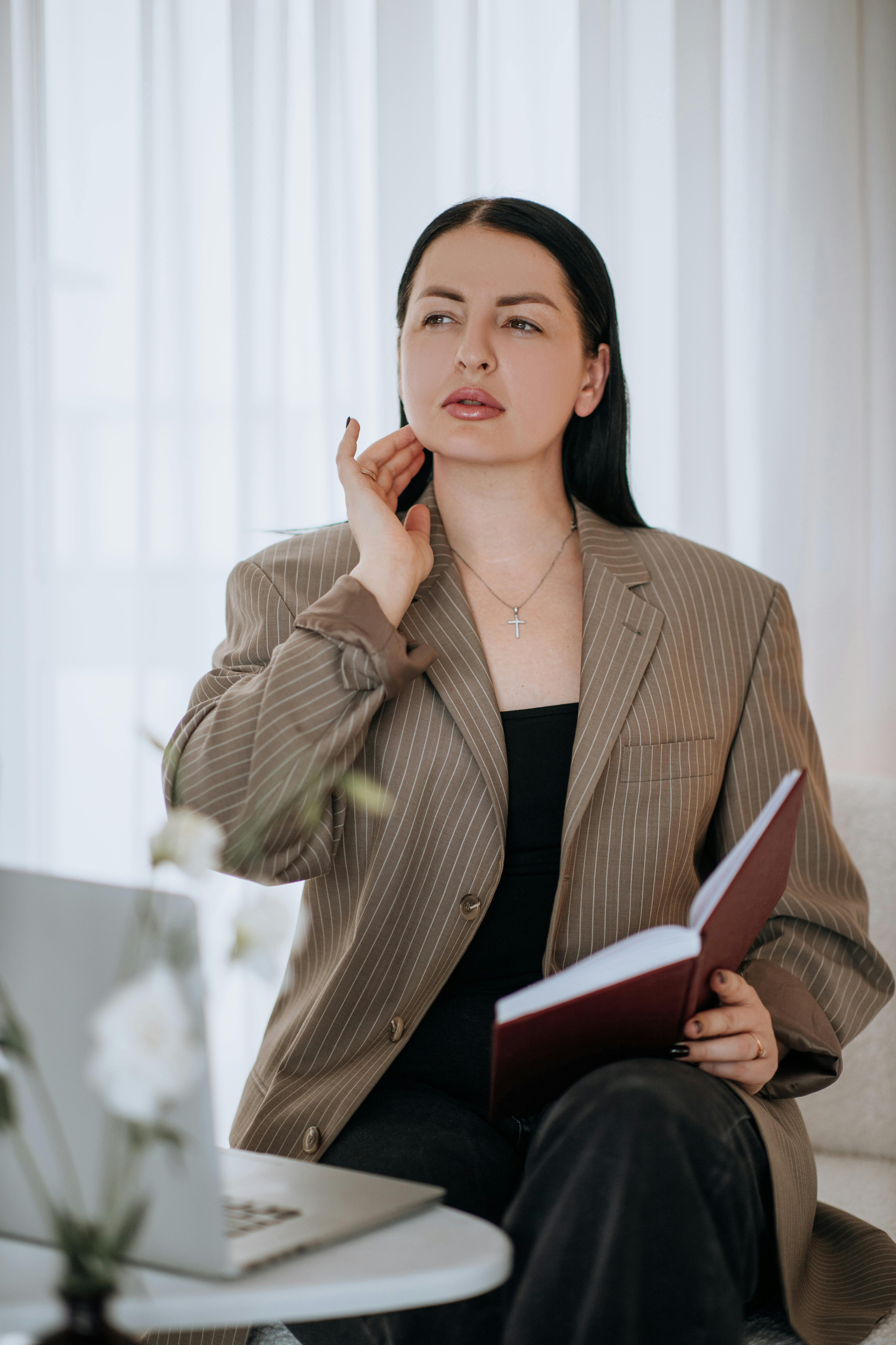 Ilmainen Ammattimainen nainen bisnesasuissa pitelee muistikirjaa ja vilkaisee mietteliäästi sisälle. Kuvapankkikuva