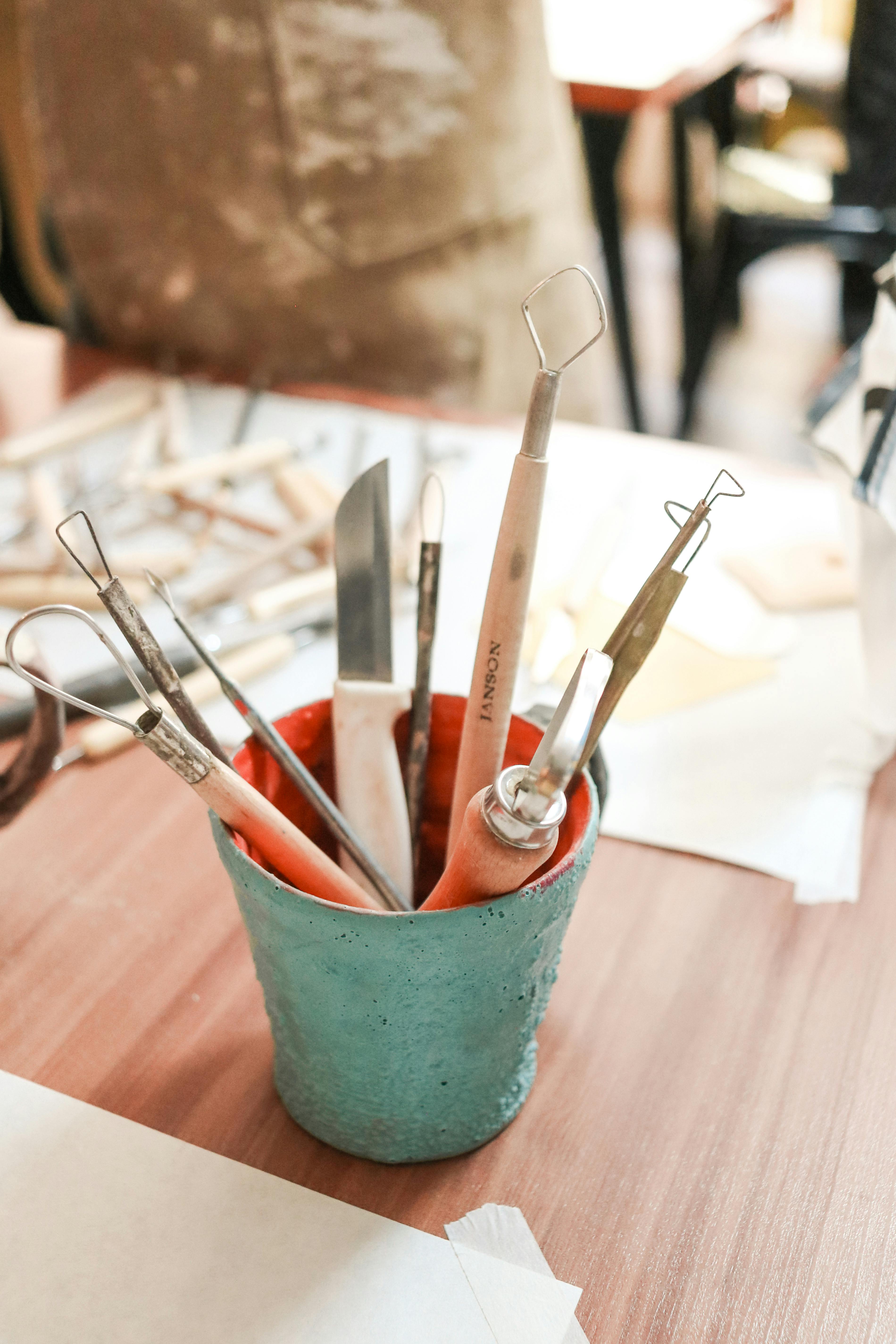Crafting clay sculpting tools in a pot on a wooden desk, ideal for artists and hobbyists.