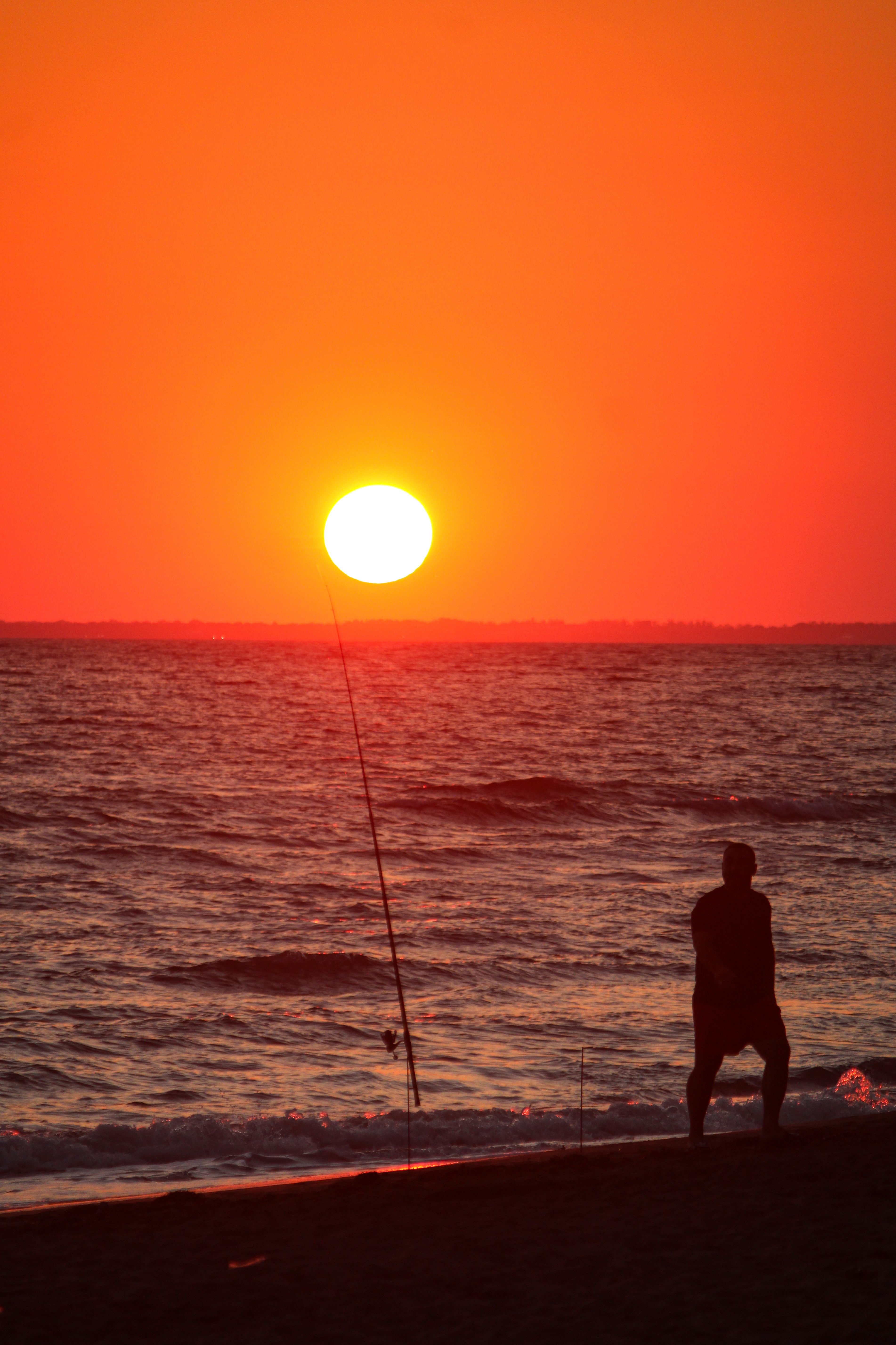 Silhouette of a Beach Fisherman at Sunset · Free Stock Photo