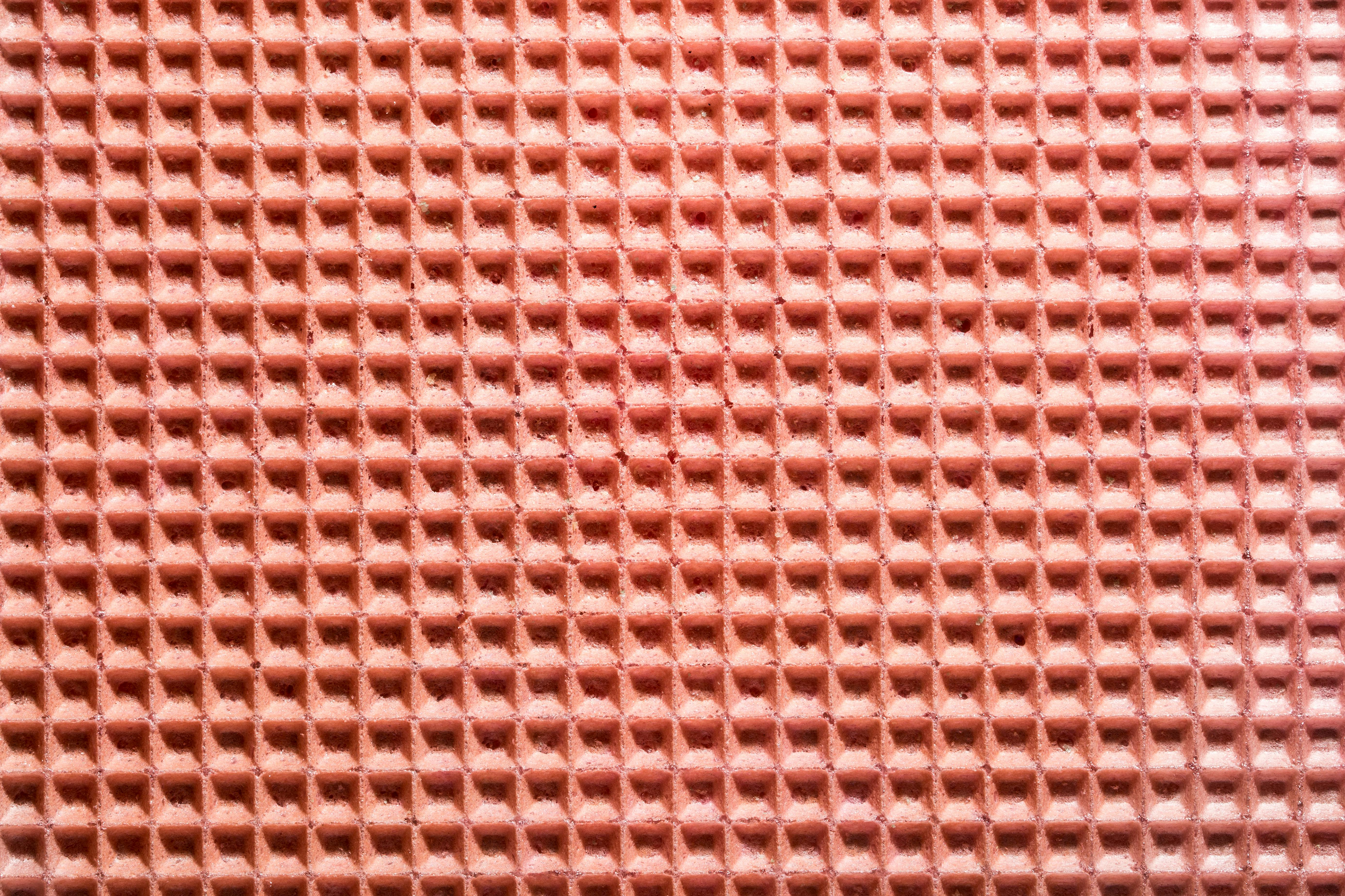 Free Detailed close-up image of a pink waffle texture with even grid patterns. Stock Photo