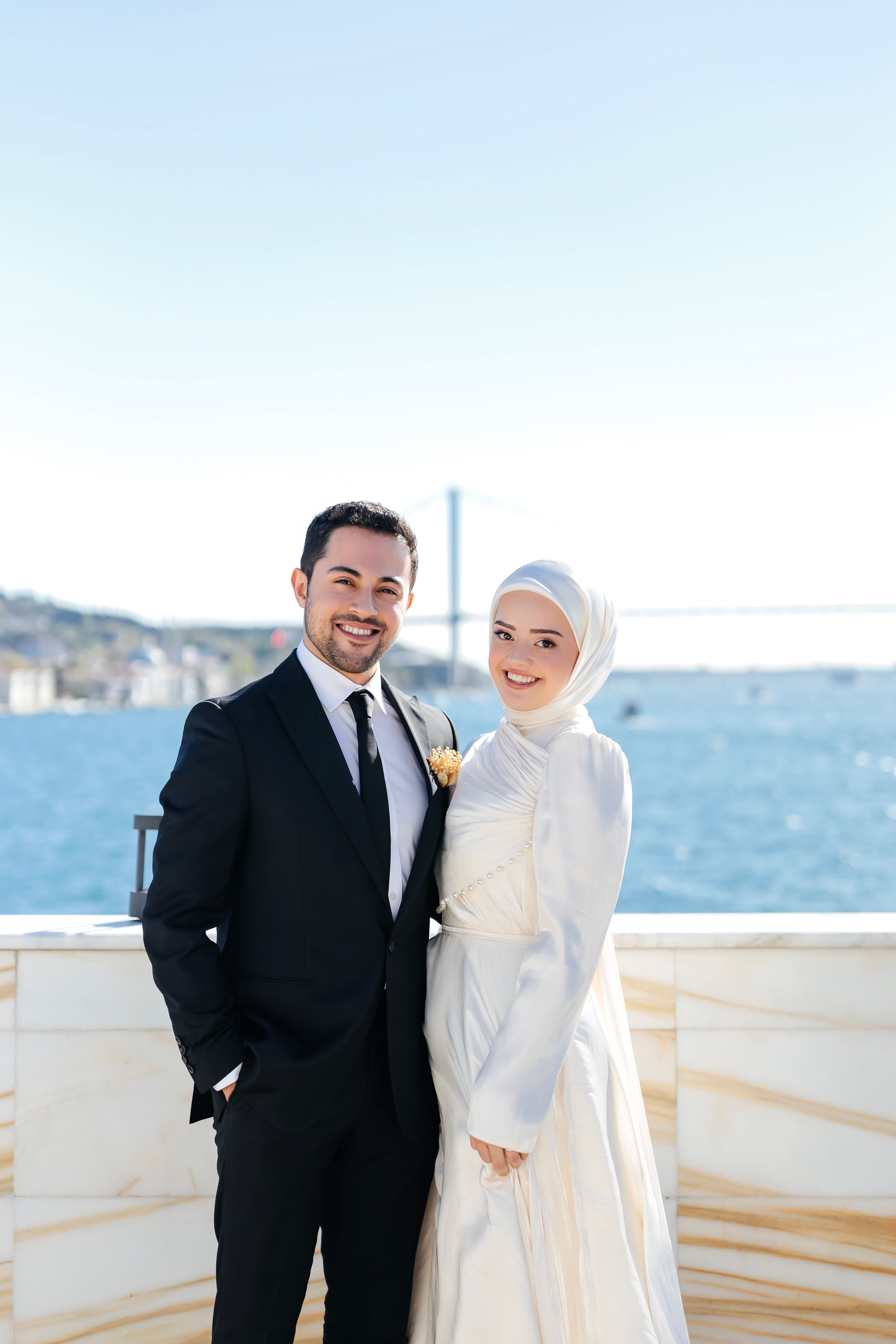Happy couple posing outdoors with a scenic bridge view, perfect for wedding themes.