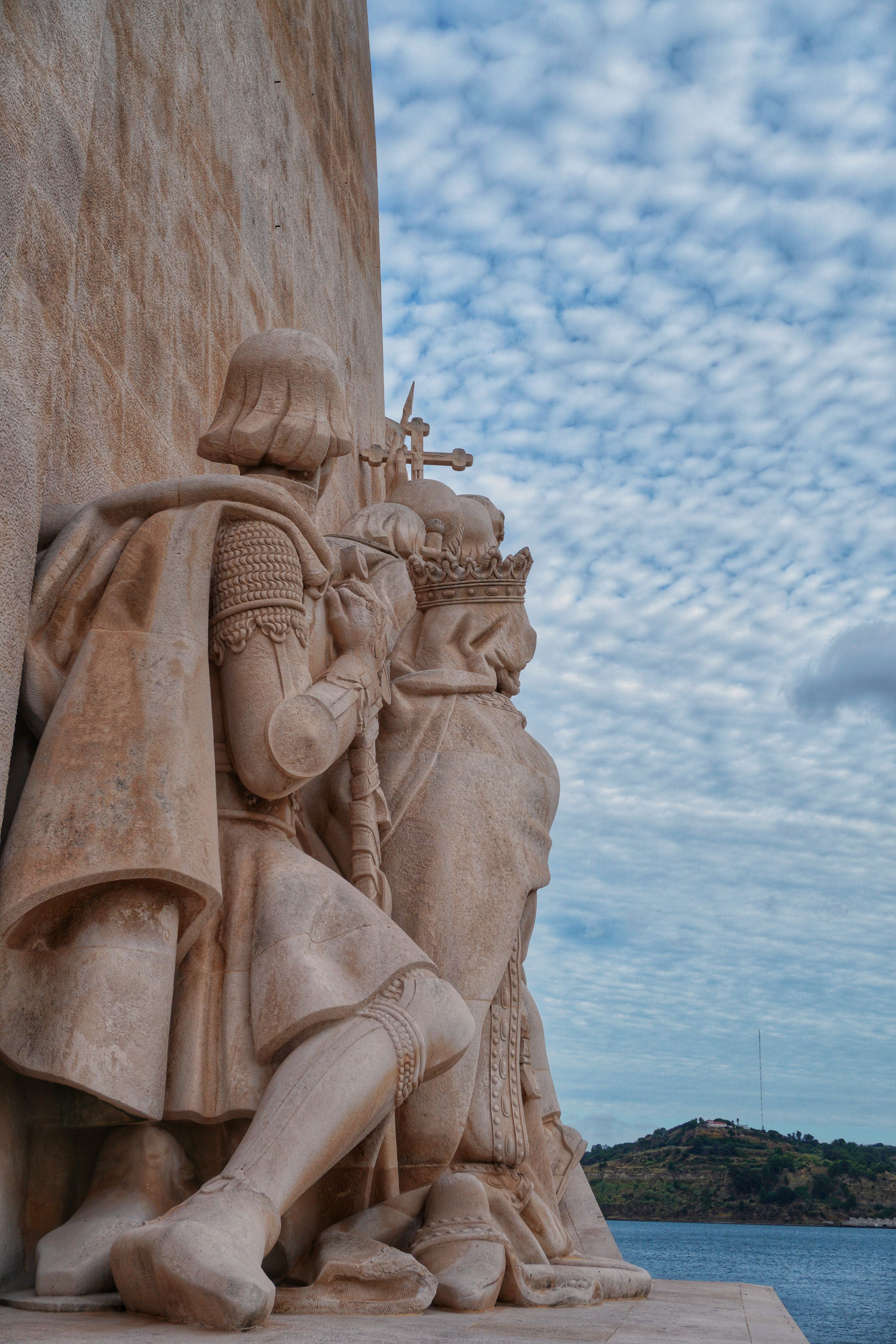 Statue of explorers at the Monument to the Discoveries in Lisbon, Portugal, under a cloudy sky.