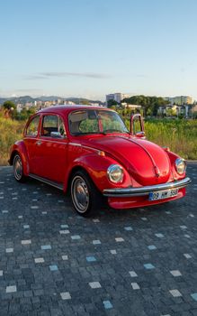 A vintage red Volkswagen Beetle parked outdoors. Classic car under clear blue sky.