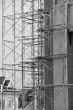 Monochrome image of scaffolding on a brick building under construction.