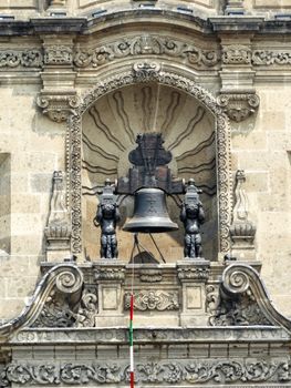 Ornate Mexican bell tower showcasing detailed architectural design and flag during daylight.