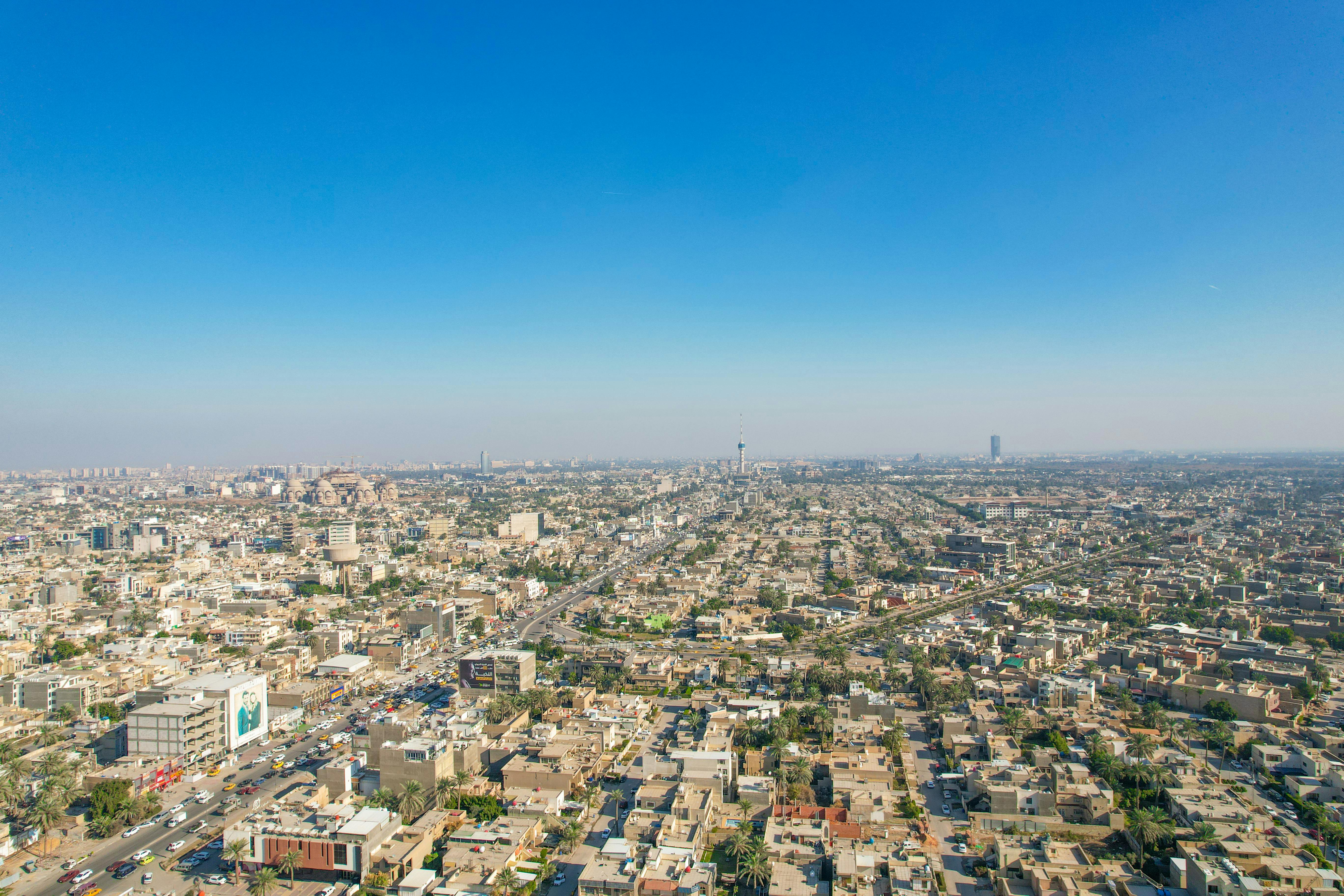 Aerial view of Baghdad cityscape showcasing buildings and a clear horizon under a blue sky.