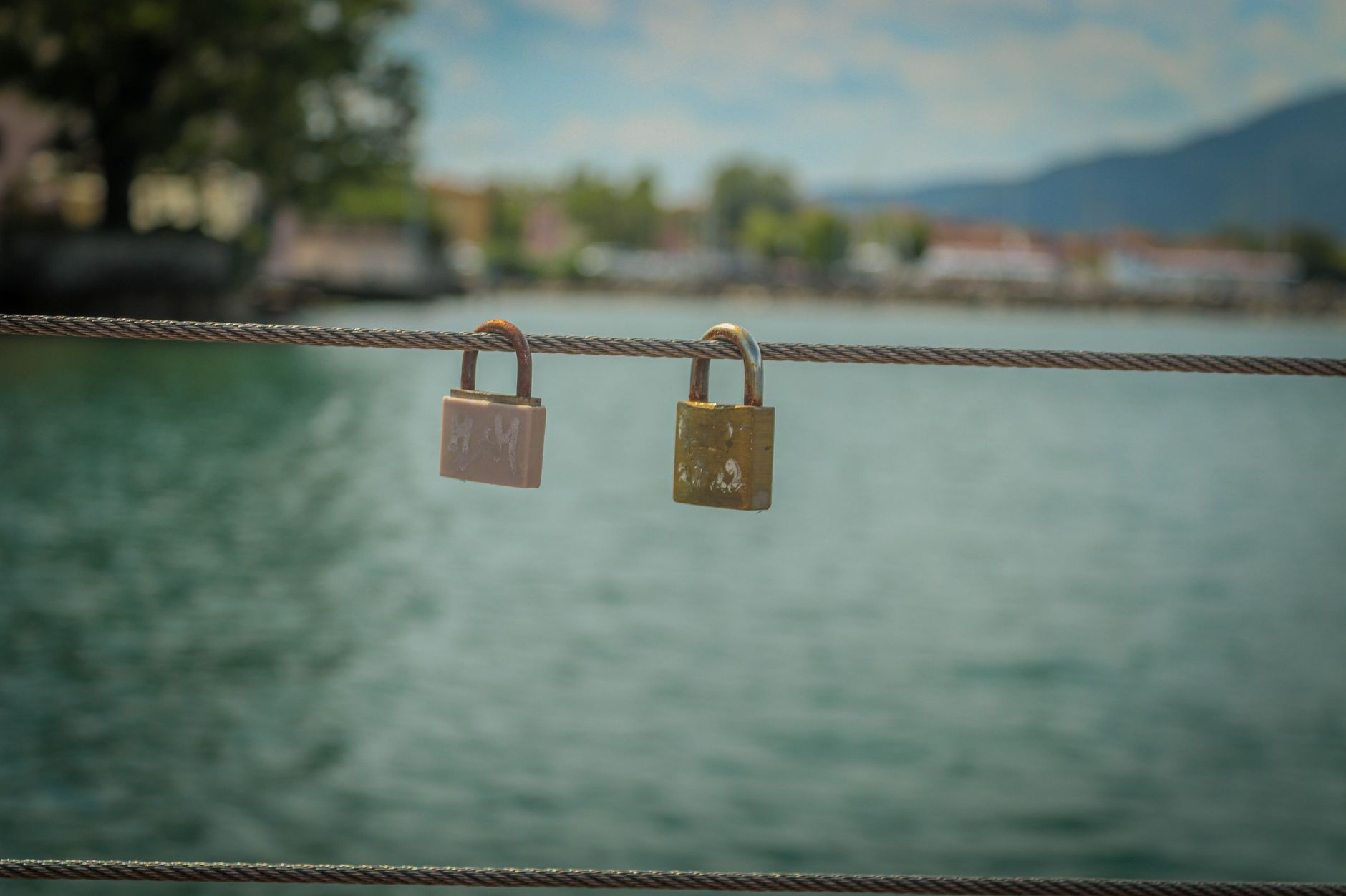 A pair of love padlocks on a railing, symbolizing enduring romance against a serene water backdrop.