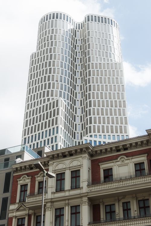 Free A towering modern skyscraper contrasted with historic architecture under bright daylight. Stock Photo