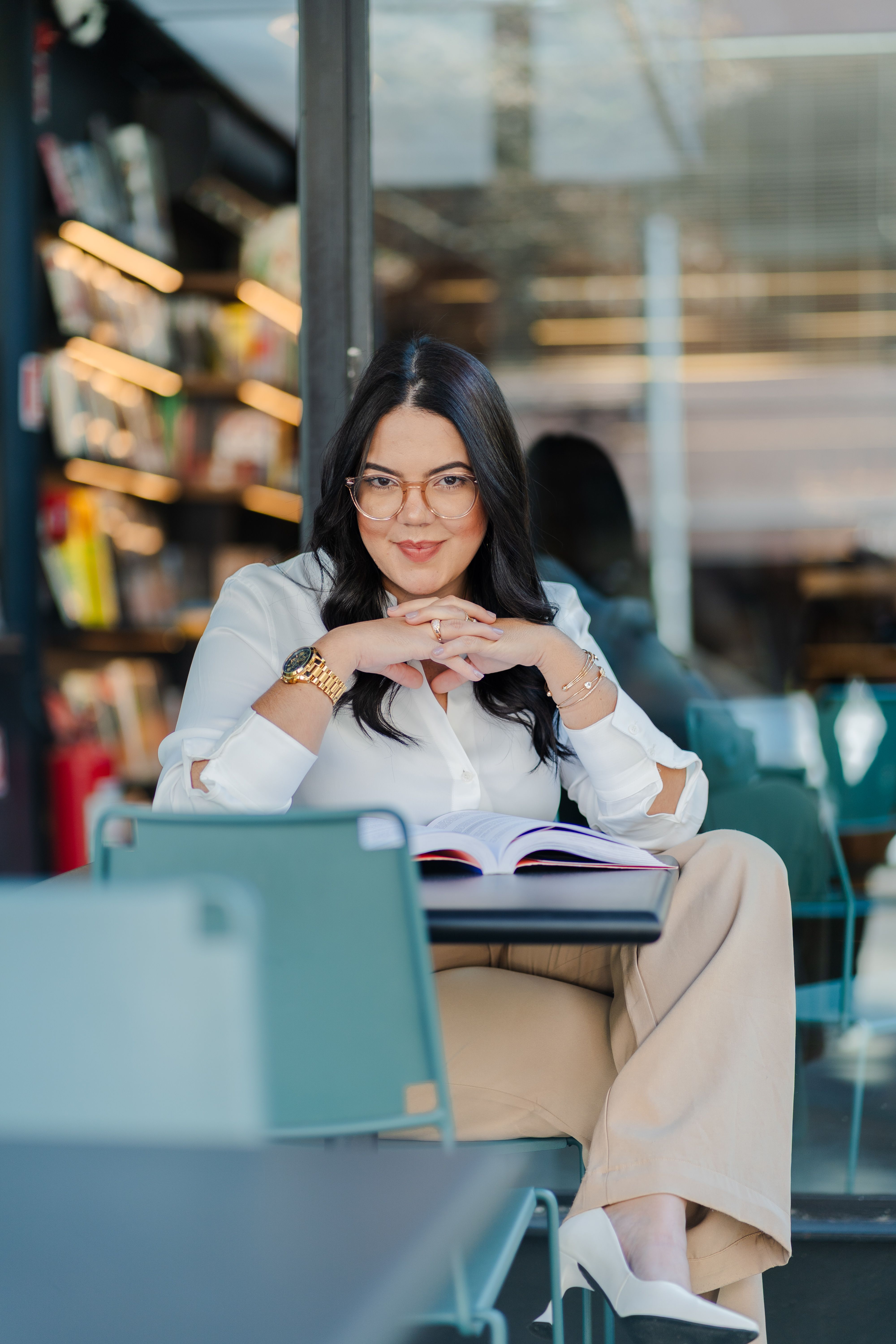 Stylish woman reading a book in a modern library, exuding confidence and sophistication.