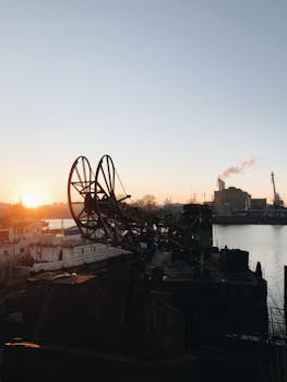日出时分，基辅的一个工业港被捕捉到，起重机和机械的轮廓映衬在温暖的天空中