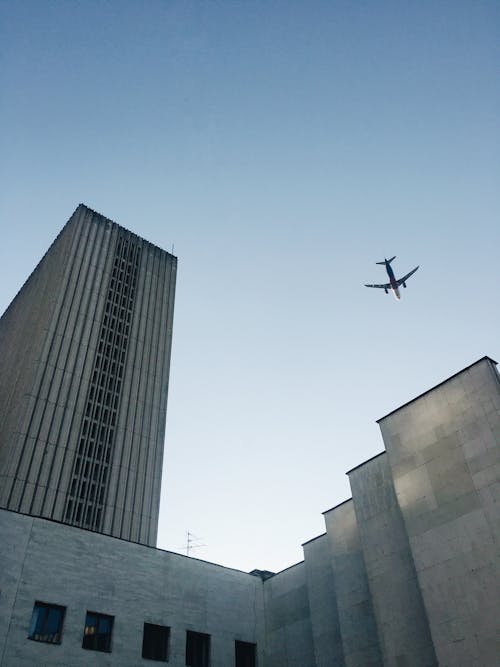 Free Low Angle Photo of Airplane Flying Over Building Stock Photo