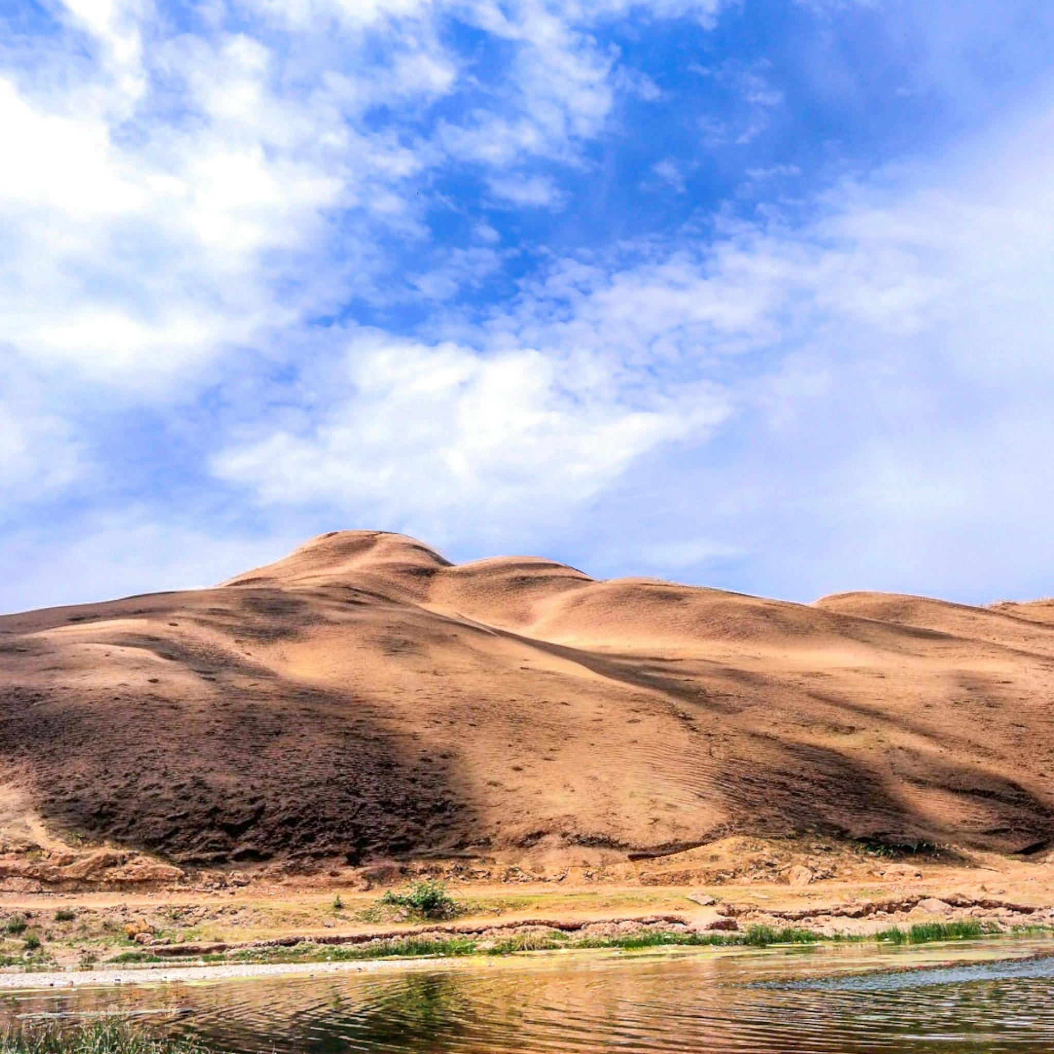Beautiful sand dunes and blue sky reflecting in water, capturing India's natural landscapes.