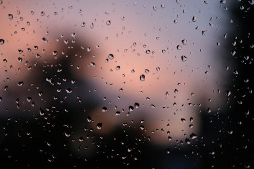 Close-up of raindrops on glass with a sunset backdrop, creating a serene and artistic effect.
